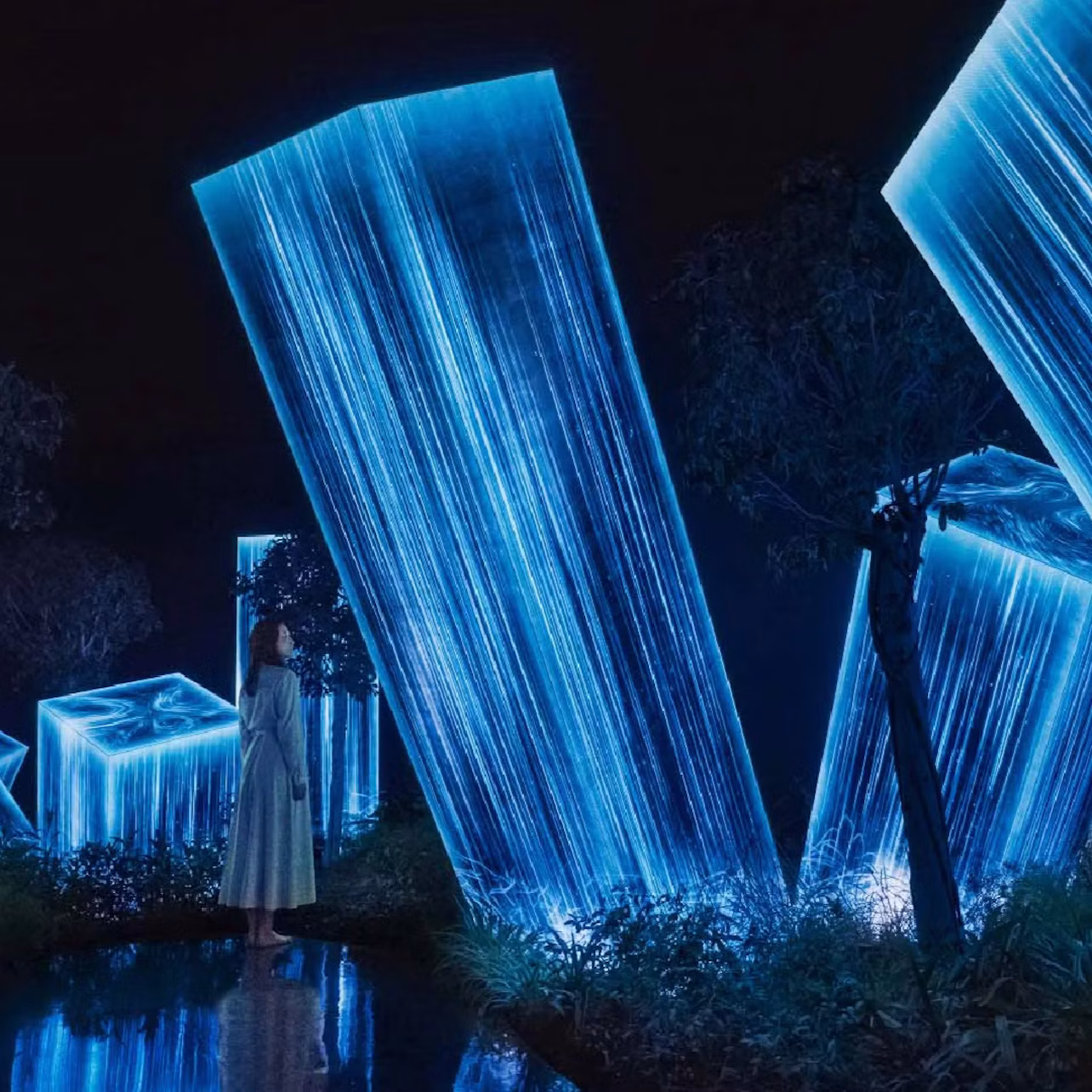 A woman stands in a dark environment surrounded by glowing blue crystalline structures and trees.