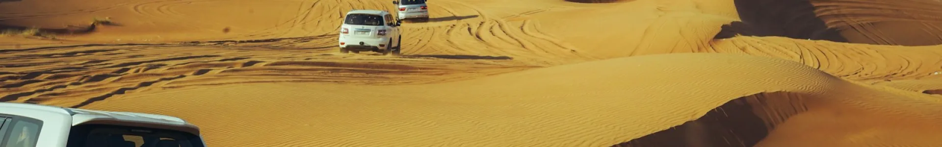Convoy of 4x4 safari vehicles crossing the sand dunes in Dubai