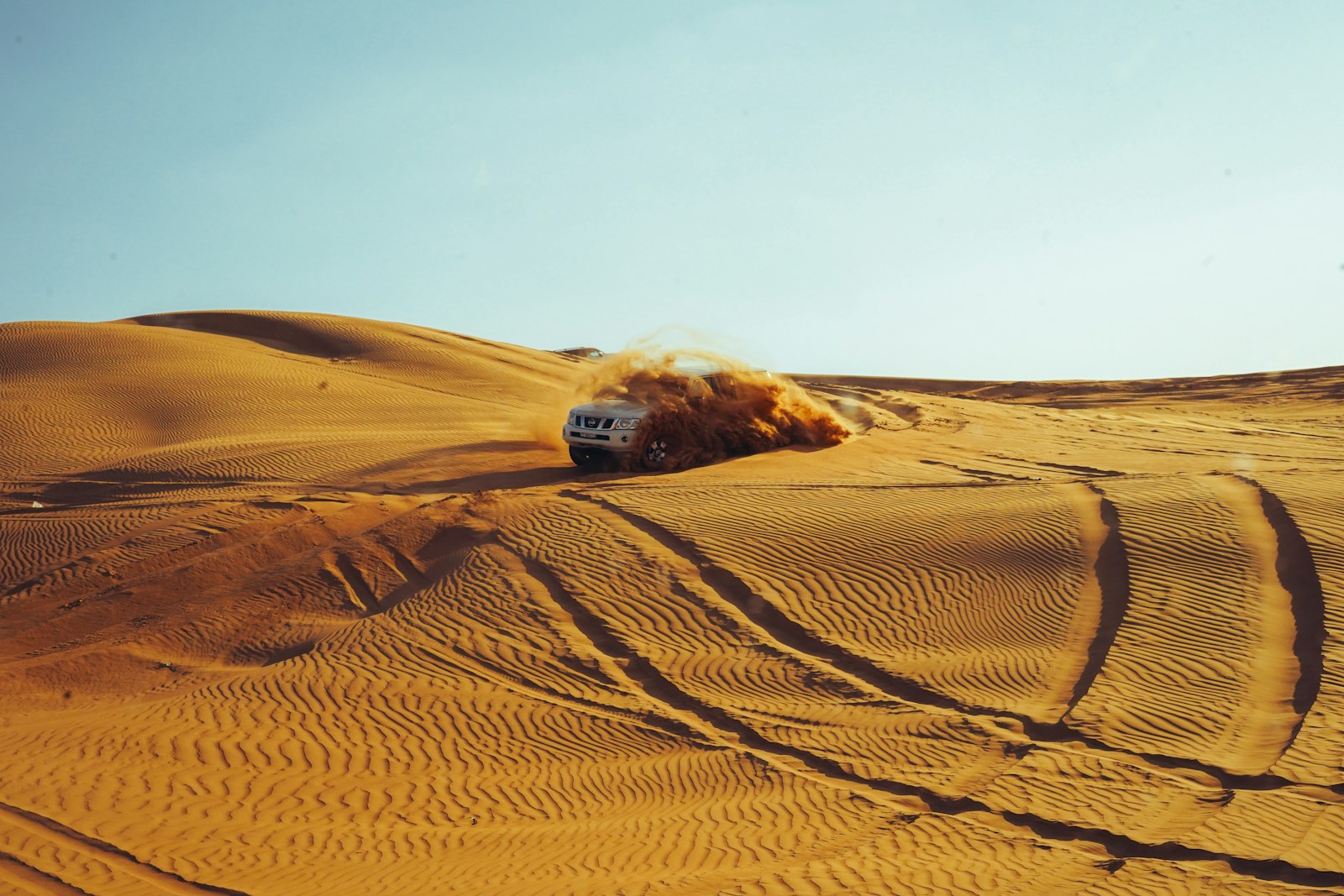 A four-wheel-drive vehicle throwing up sand during dune bashing in the Dubai desert
